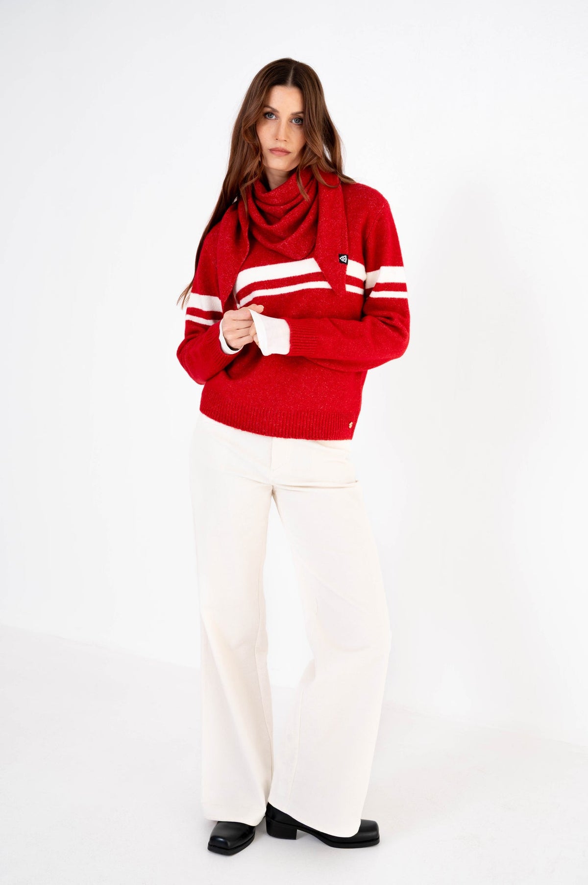 dame draagt een offwhite broek gecombineerd met een rode trui