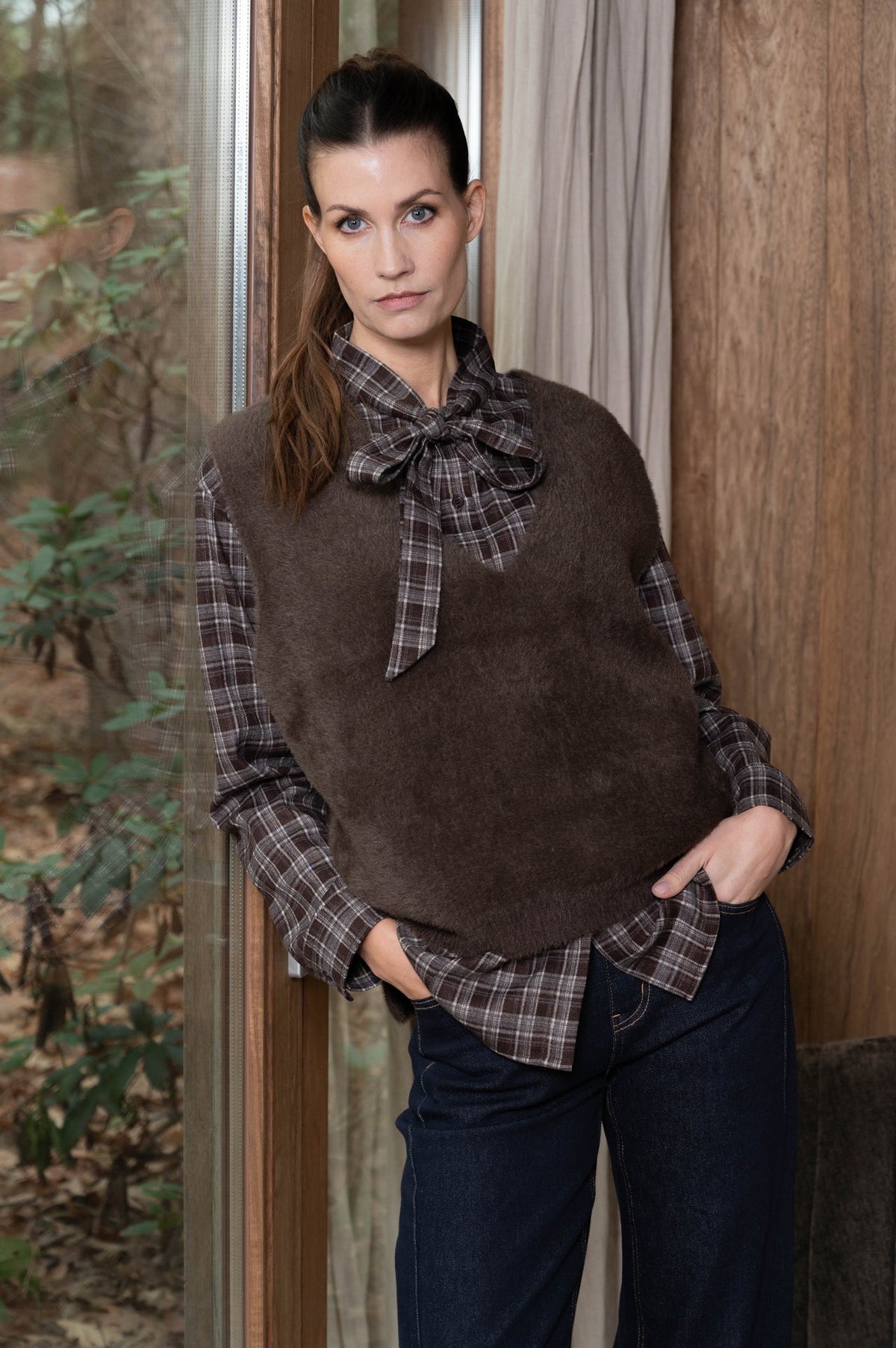 vels zachte bruine top met v-hals, zonder mouwen over een bruin geruite blouse met strikkraag