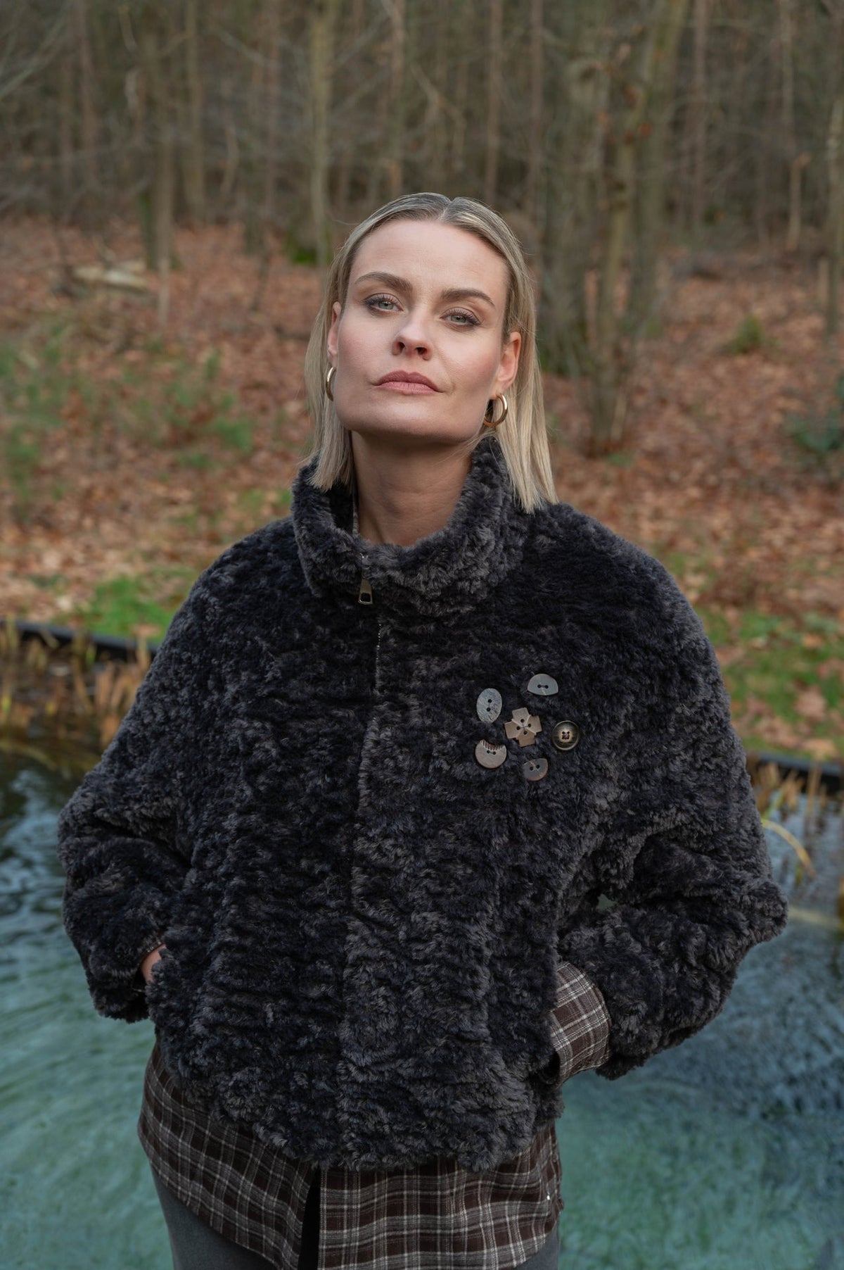dame draagt een zwartgrijs zacht teddyjasje over een geruite herfstblouse 