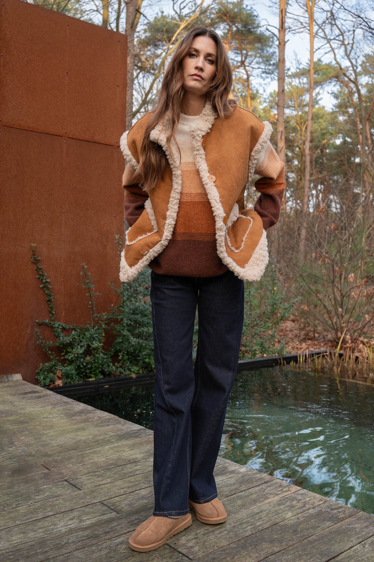 dame draagt een herfstoutfit met warme kleuren en gilet als een extra laag over de trui 