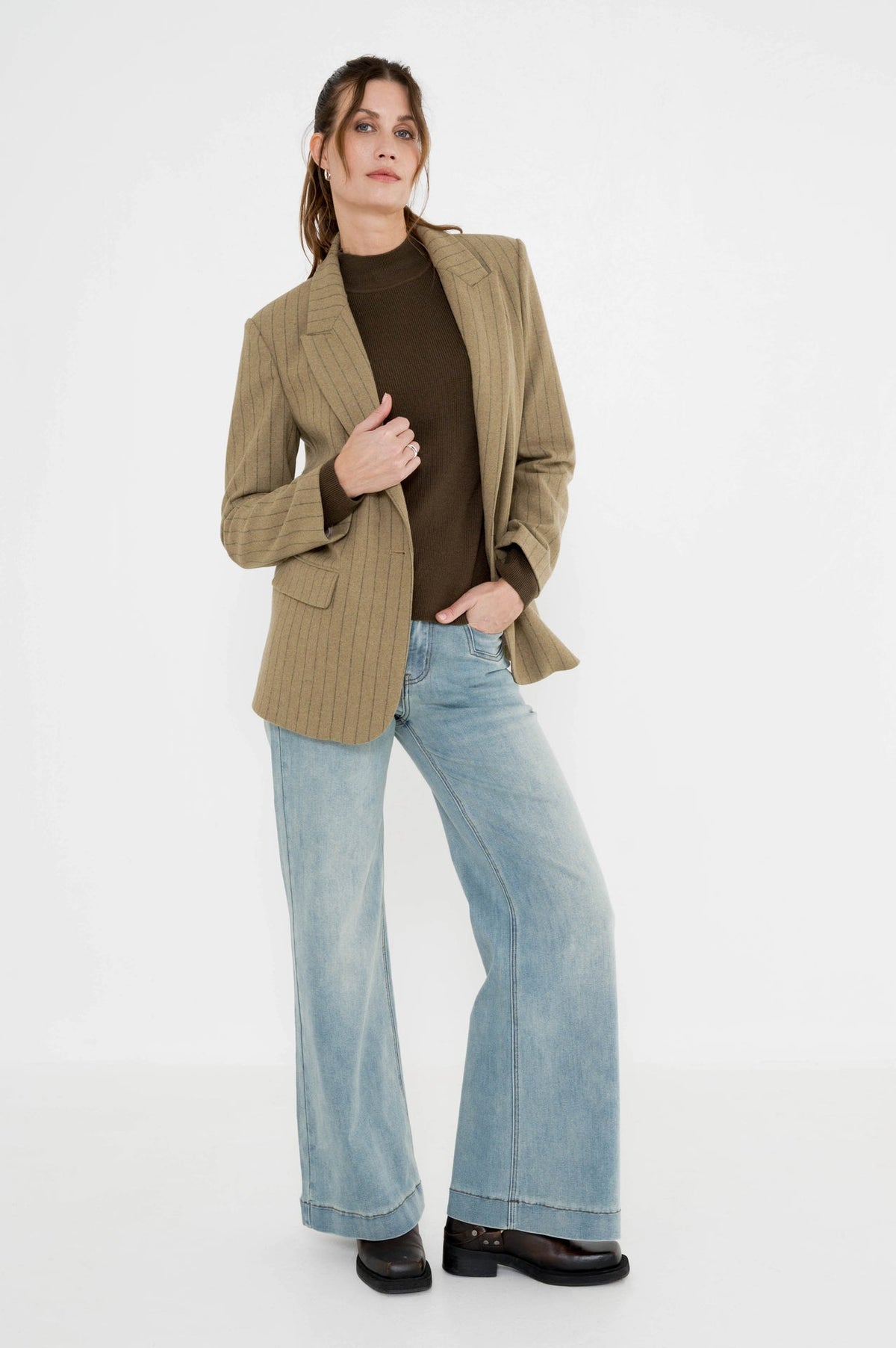 dame draagt de coltrui phenix mosgroen in combinatie met rora blazer khaki gestreept op een lichte spijkerbroek