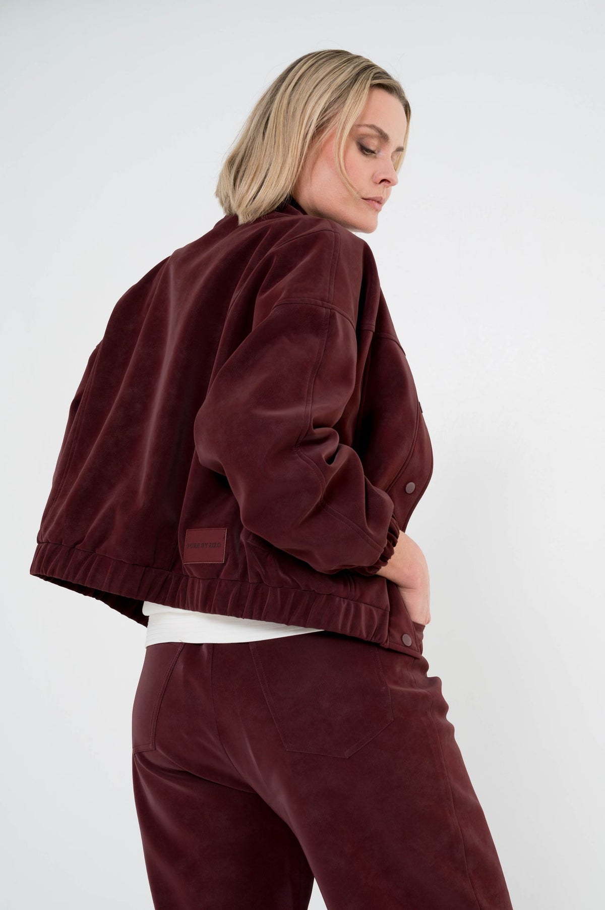 model showt achterkant van wijnrode broek brooke met een passend jasje erboven als complete set