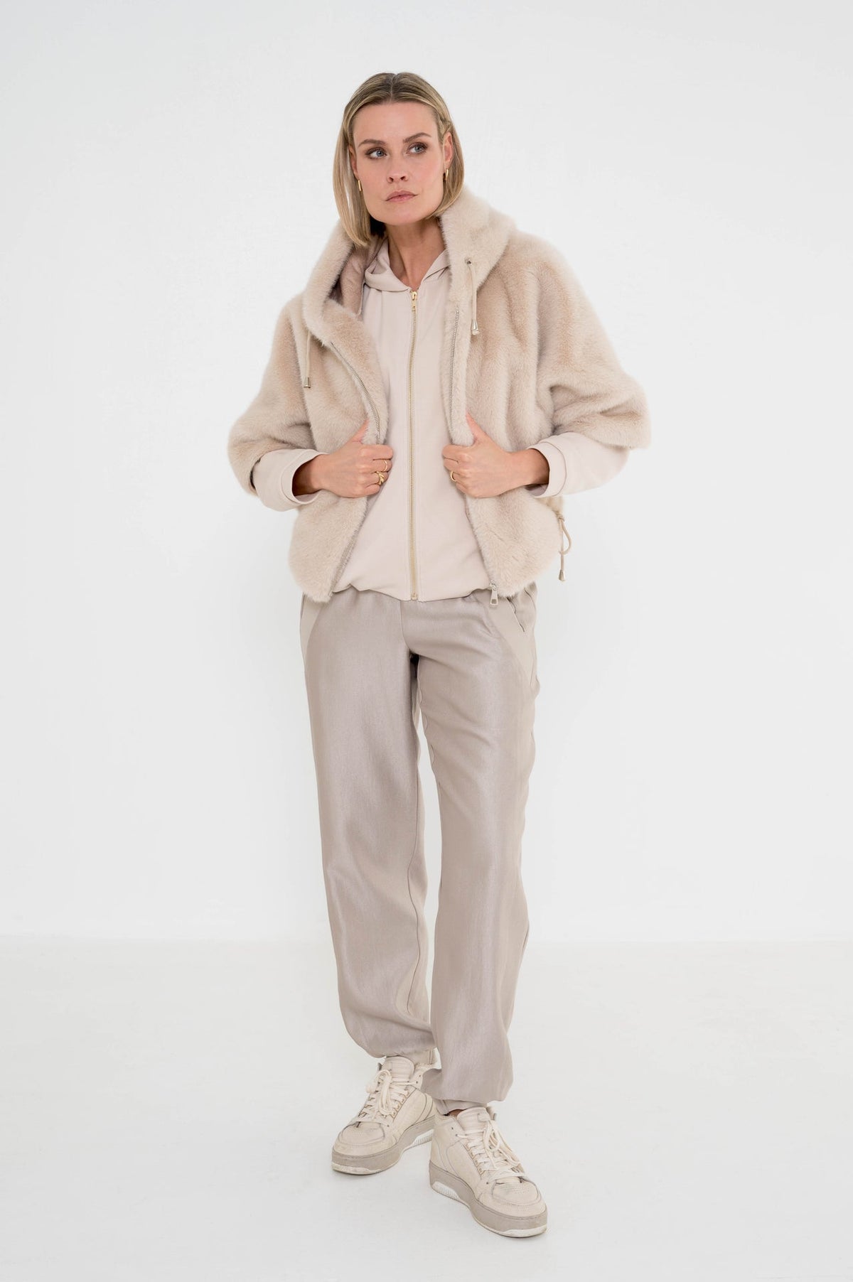 trendy outfit dames met een zandkleur vest, greige broek en over het vest een zacht zandkleur jasje met korte mouwen