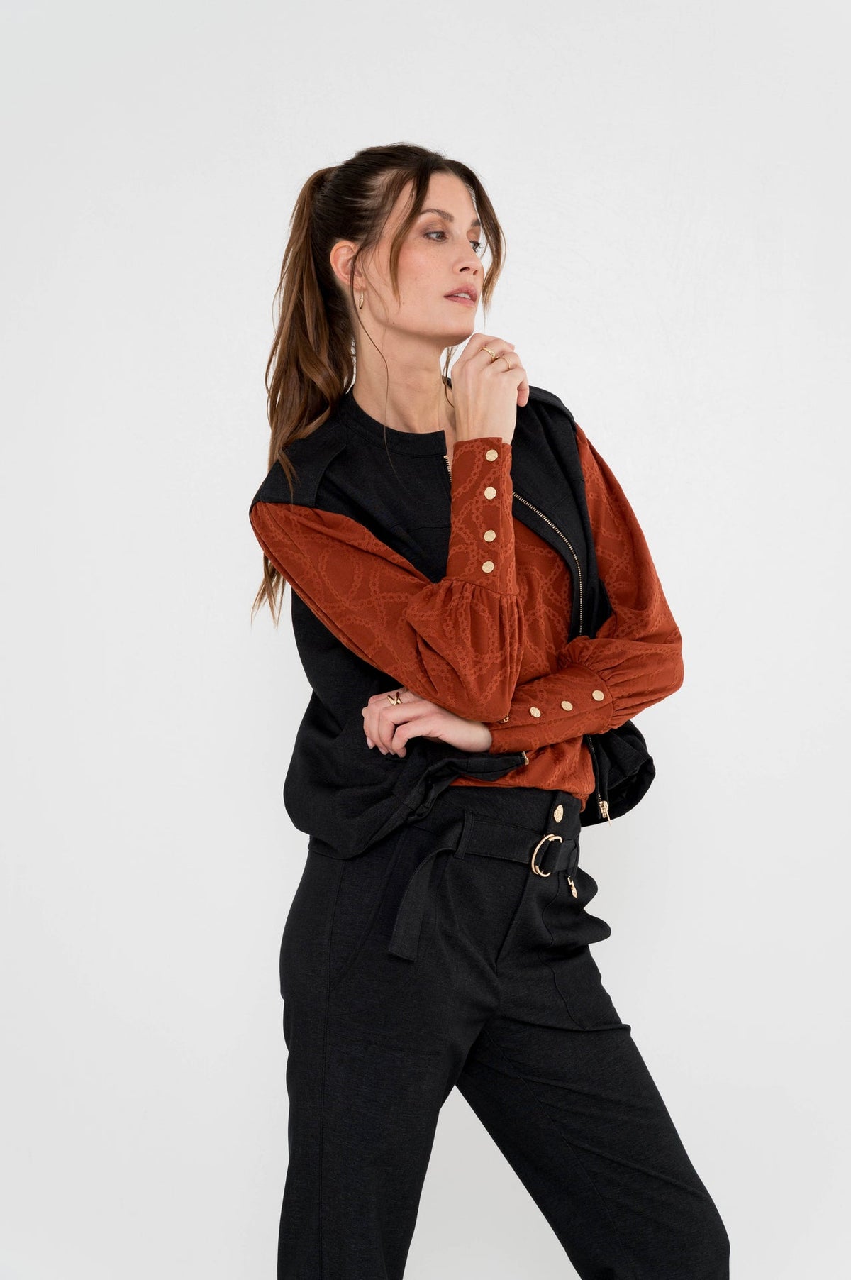 model draagt roestbruin shirt vazan met een zwarte broek en over het shirt een bodywarmer jasje