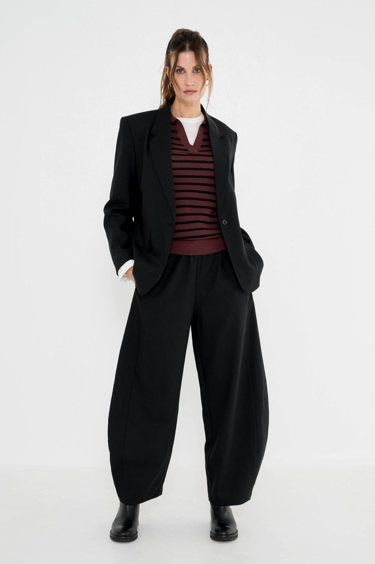 dame heeft de wijde barrel pantalon zwart met een zwarte blazer gecombineerd