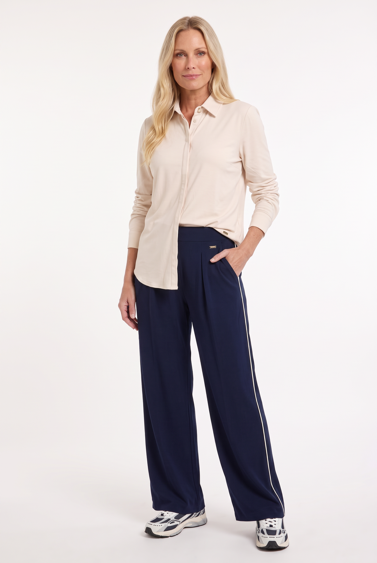 model draagt donkerblauwe sportieve travelbroek met offwhite bies aan de zijkant met daarboven een offwhite travel blouse