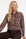 vrouwelijke travelblouse met kleurrijke panterprint op een bruine broek