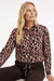 vrouwelijke travelblouse met kleurrijke panterprint op een bruine broek