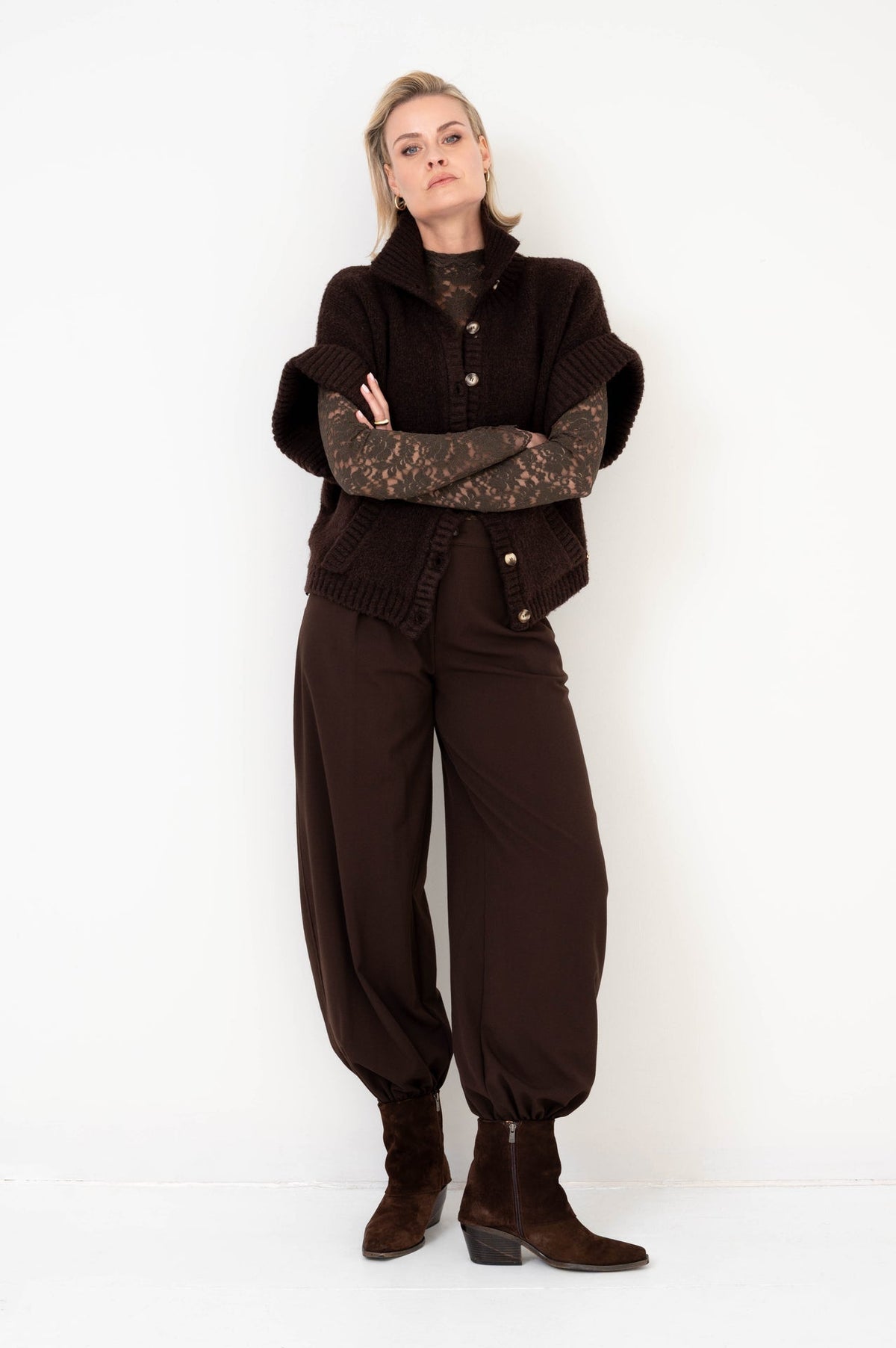 dame draagt een bruine barrel broek gecombineerd met een bruin vest en shirt