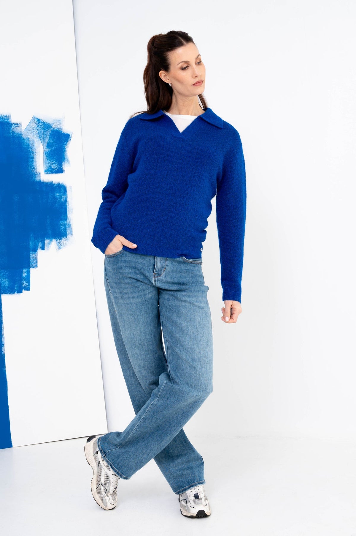 winterlook voor dames met een kobaltblauwe trui met daaronder een wit shirt op een spijkerbroek