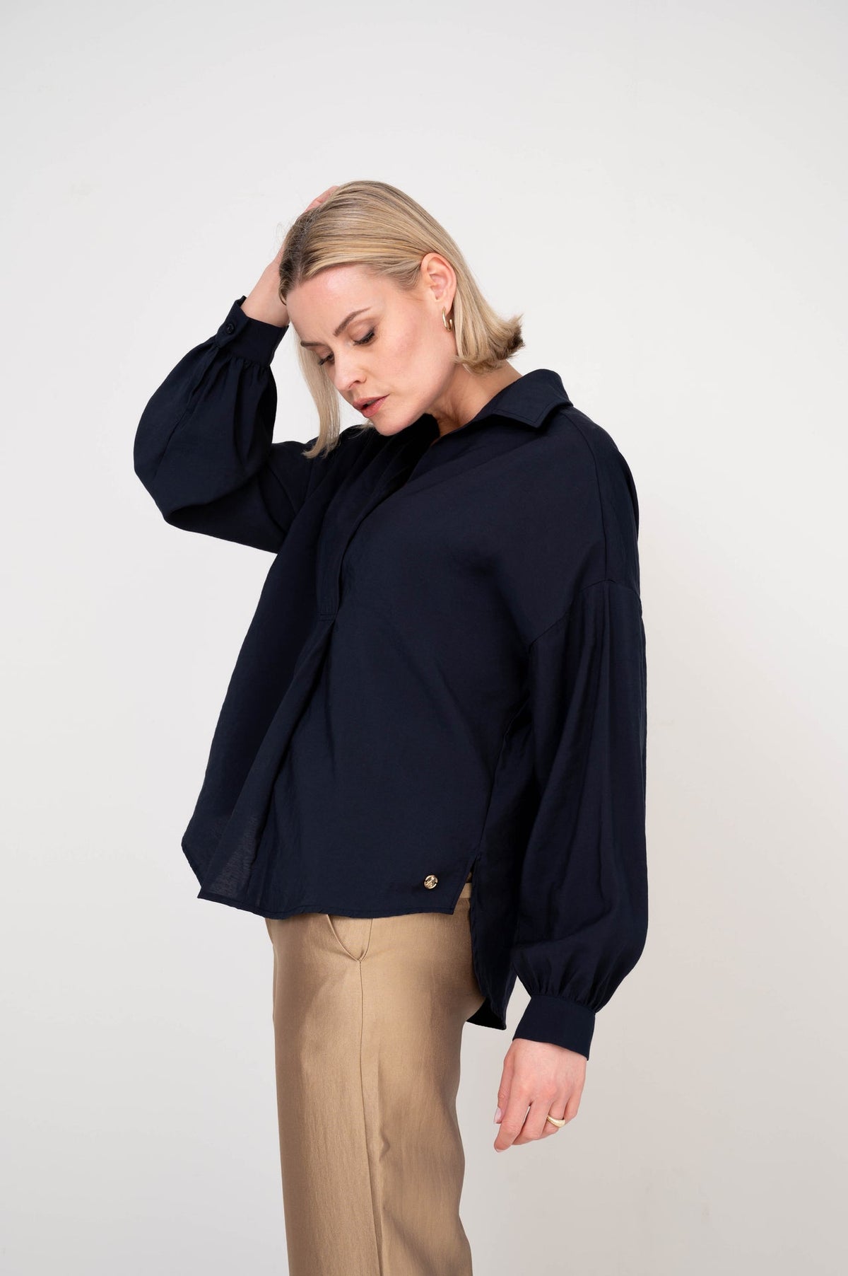 dame draagt donkerblauwe blouse op gouden broek 