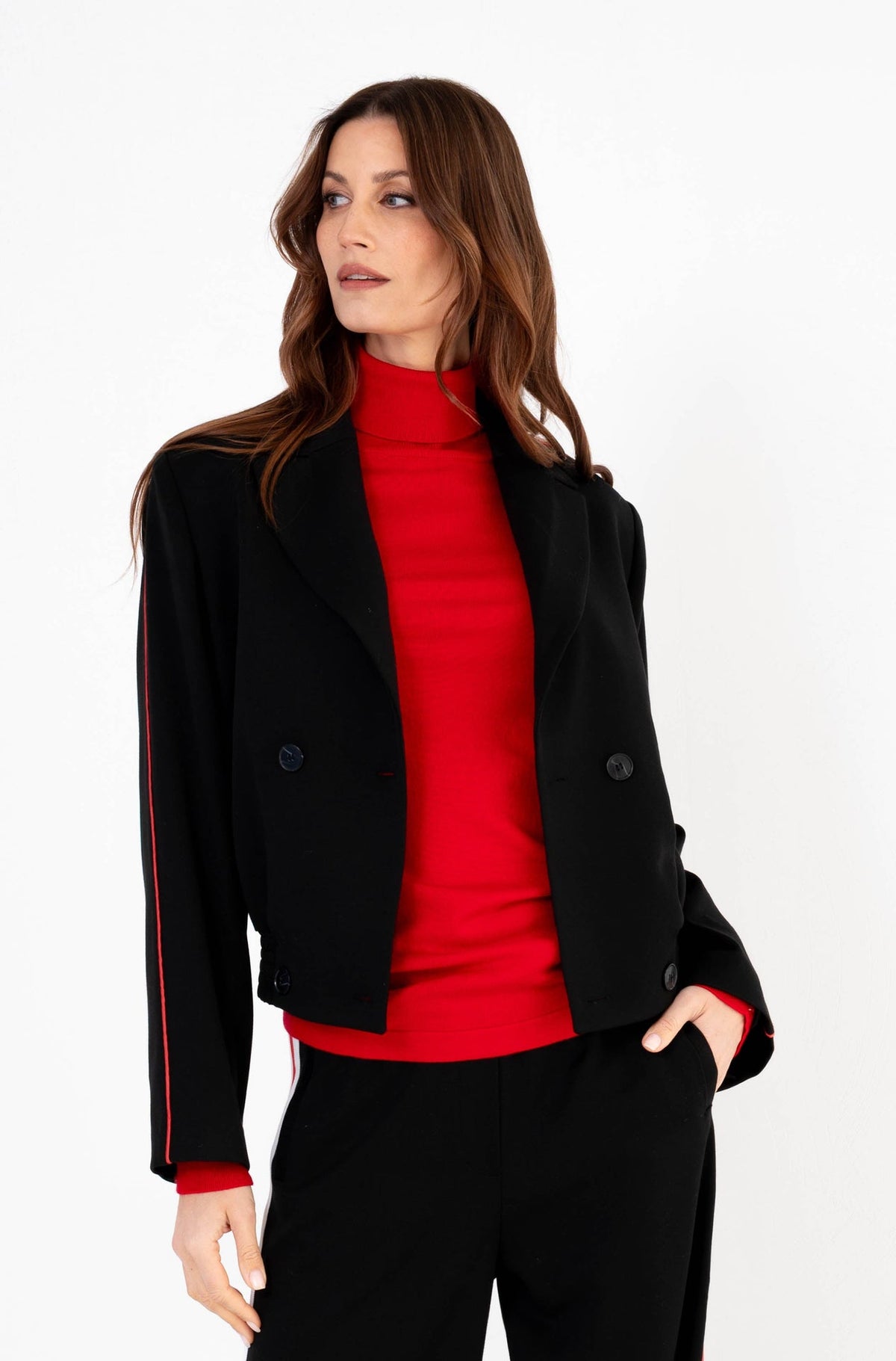 dame draagt een zwarte blazer met een rode streep aan de zijkant op een bijpassende zwarte broek 
