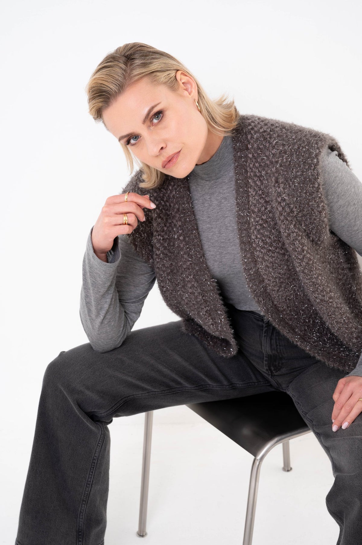 dame draagt taupe gilet zeronamet een subtiele glitterdraad over een grijs colshirt