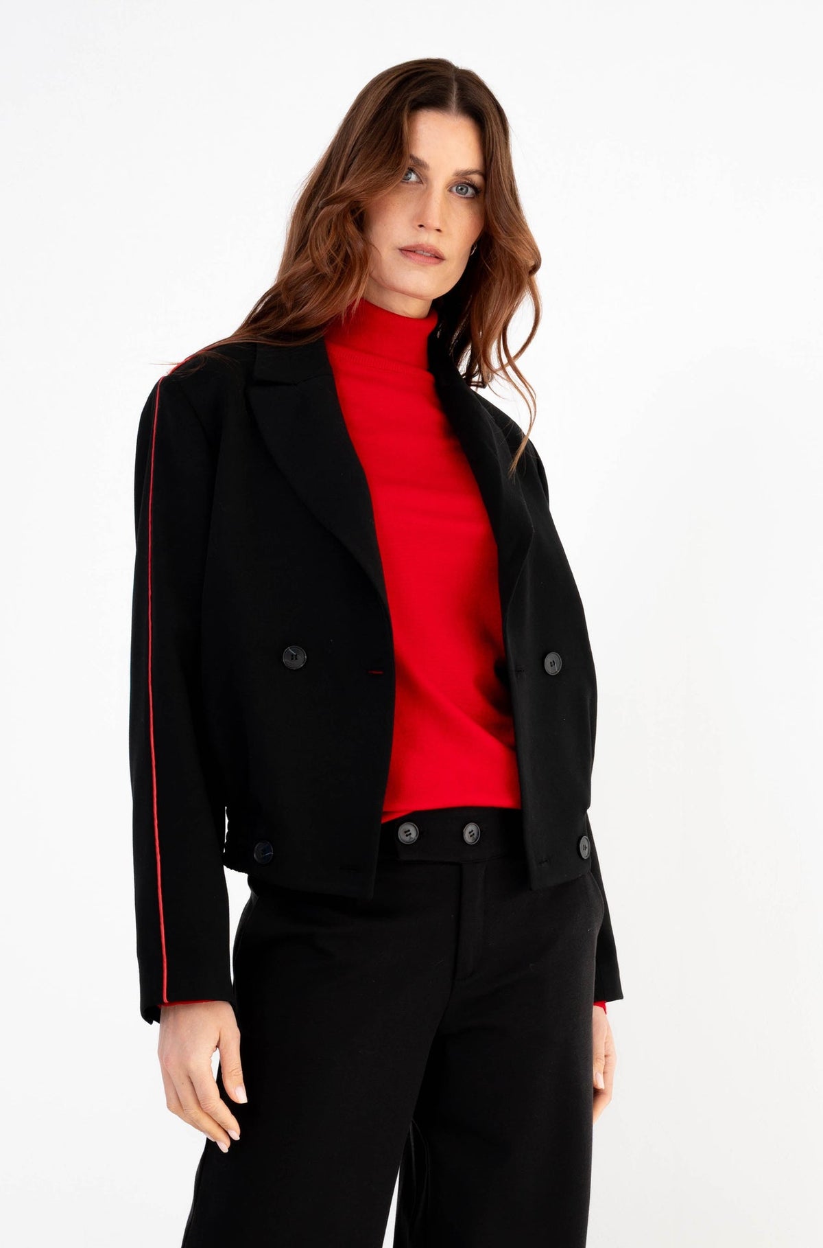 stoere outfit met een zwarte blazer met rode streep op de mouwen gecombineerd met een rode coltrui 