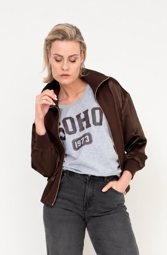 dame draagt een bruin bomberjasje met satijnlook op een grijze denim en stoer grijs t-shirt eronder