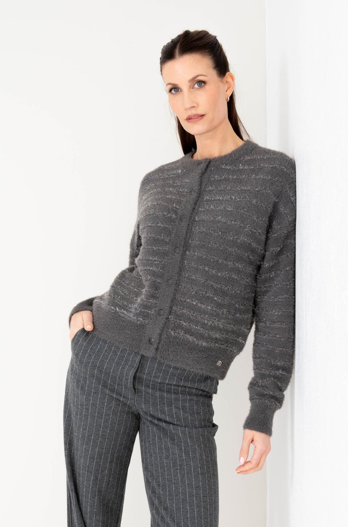 model draagt een grijs vest met lichte glitter op een gestreepte pantalon