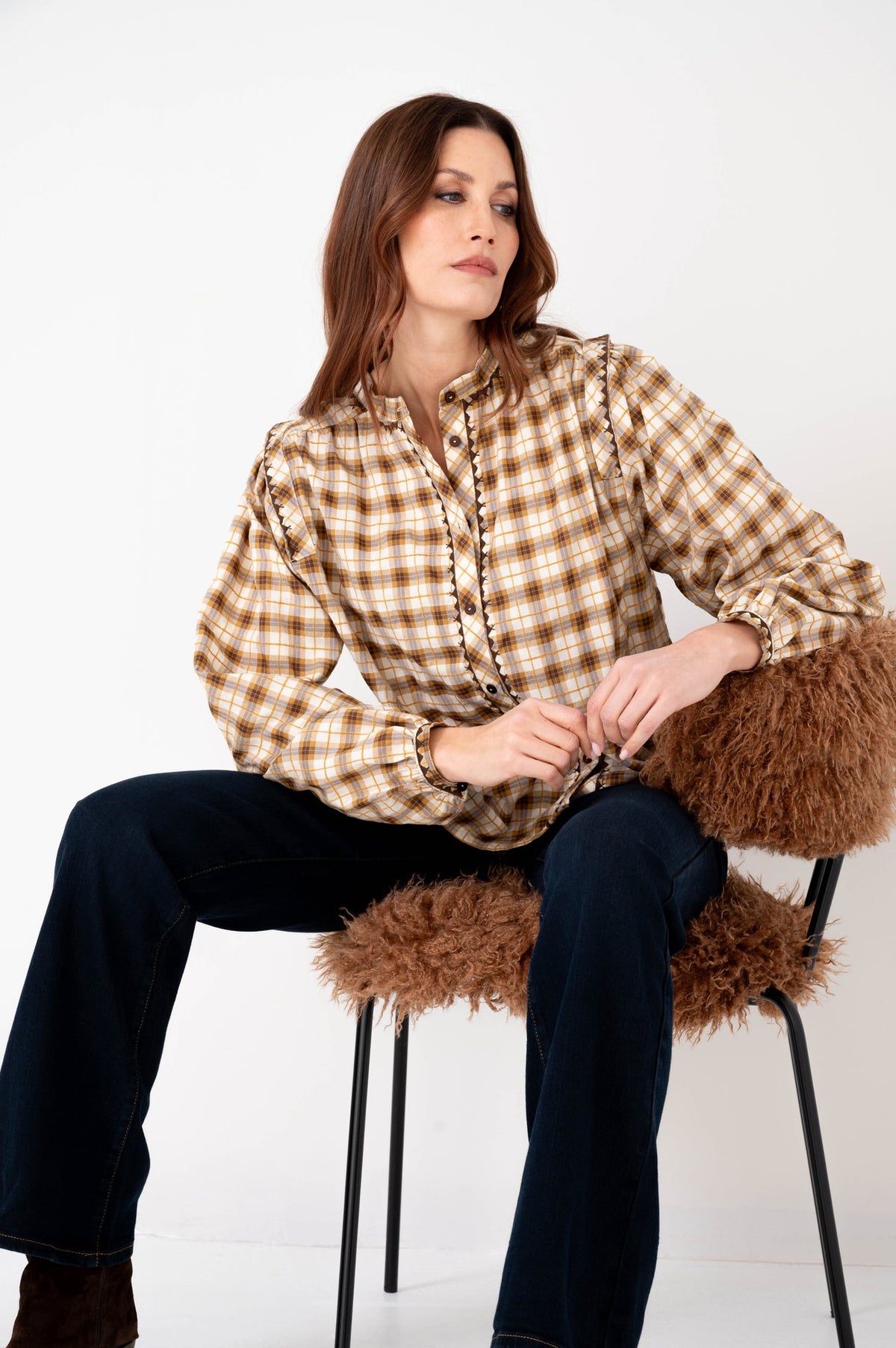 model draagt geruite blouse met warme kleuren op een donkere denim