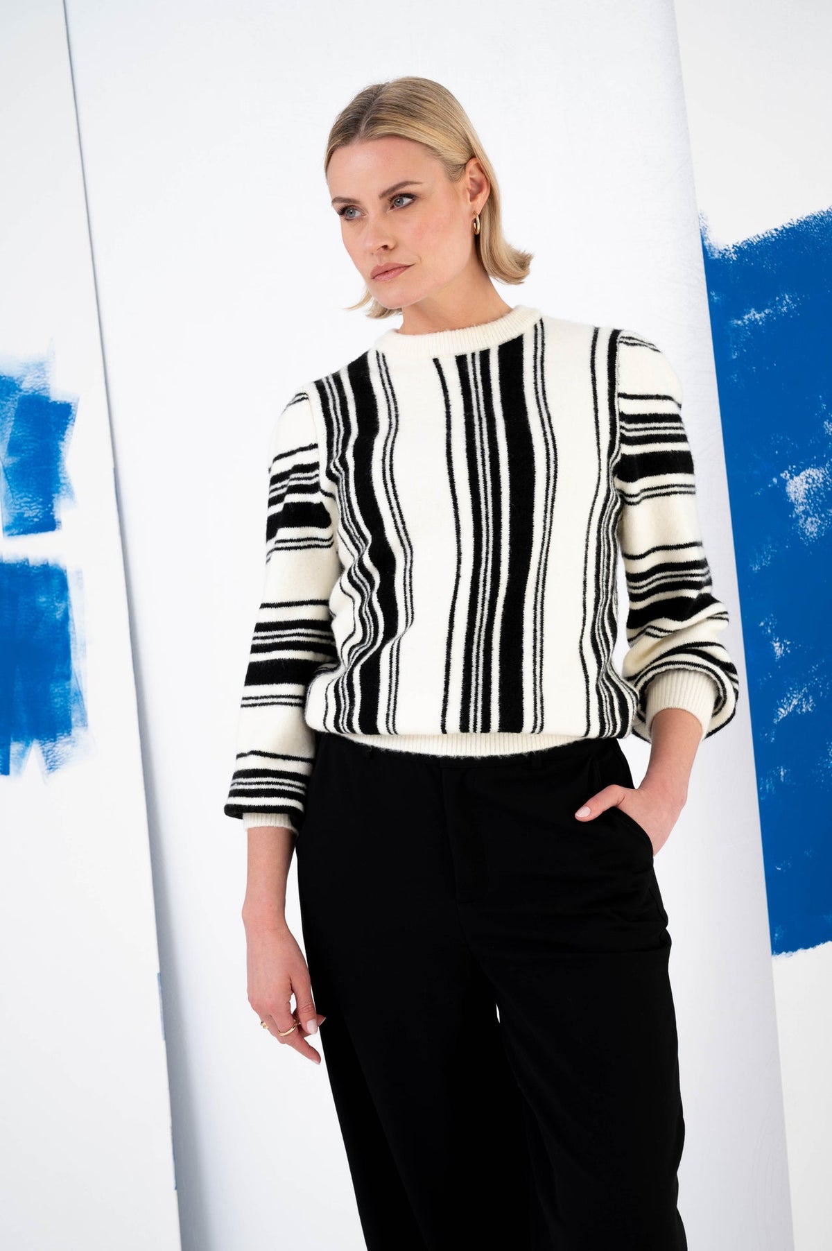 model draagt een zwart-witte trui met een grafische print op een donkere broek