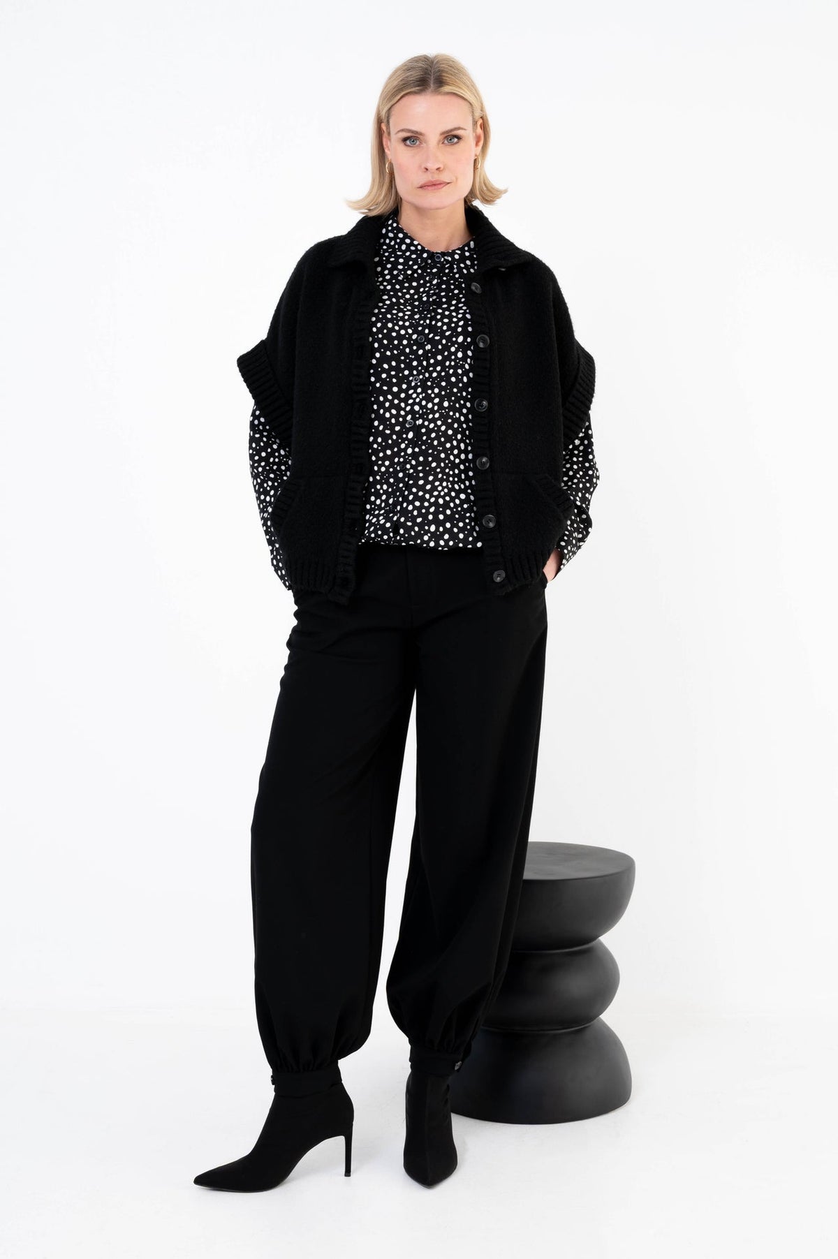 zwarte barrel broek gecombineert met een zwart vest en blouse met print