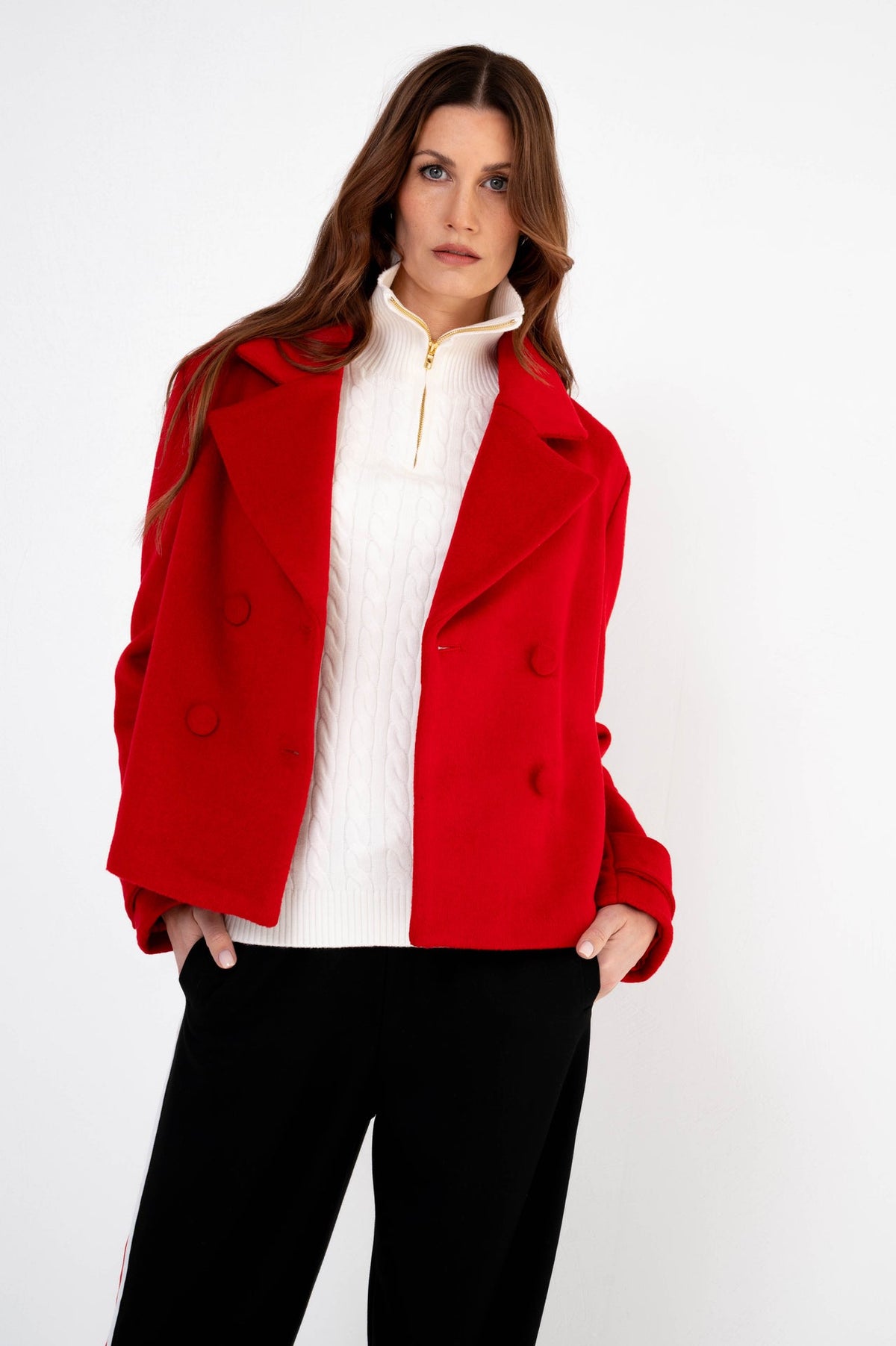 herfstlook met rode dames jas en witte trui op een zwarte pantalon 