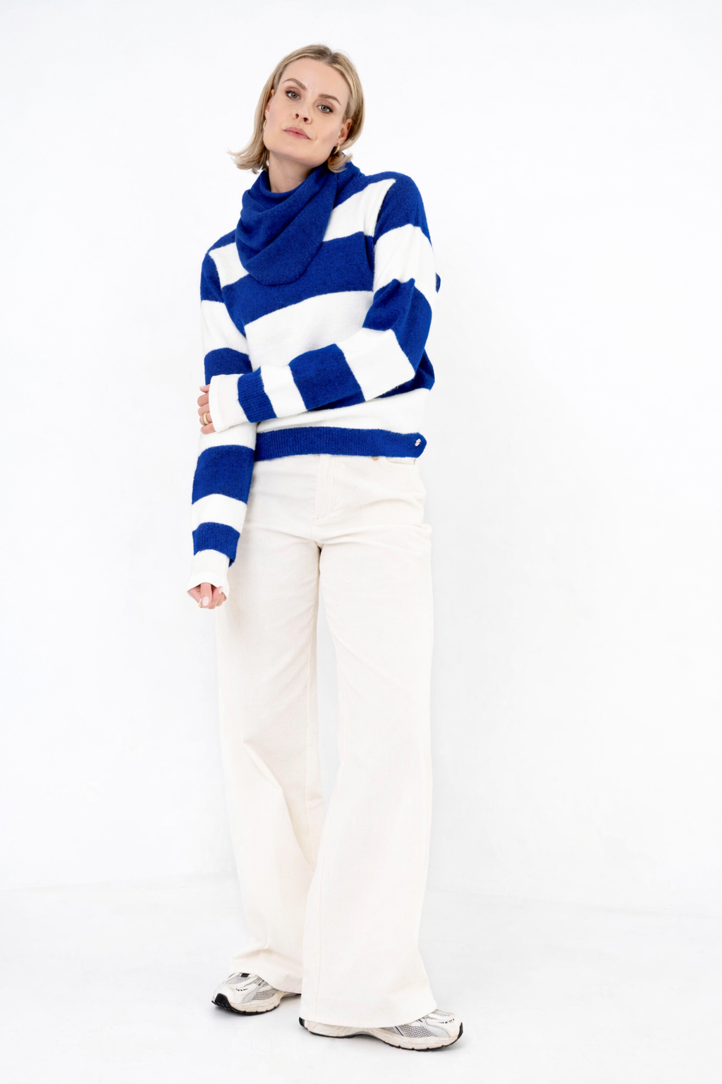 dame draagt een offwhite ribbroek met een blauw-wit gestreepte trui erboven